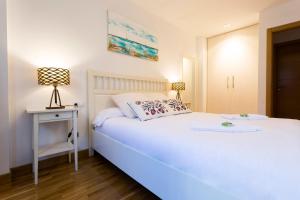 1 dormitorio con cama blanca, mesa y lámpara en Ubilla - Basquenjoy en Hondarribia