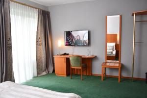 Habitación de hotel con escritorio y TV en la pared en LANDHAUS LENGEDE Hotel, en Lengede
