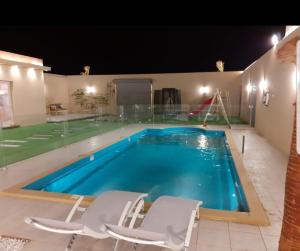 a large swimming pool with two chairs and a slide at Al Somow Chalets in Dahaban