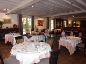uma sala de jantar com mesas e cadeiras com mesas brancas em Auberge des Pins - Teritoria em Sabres