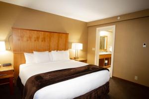 1 dormitorio con 1 cama blanca grande en una habitación de hotel en Mirabeau Park Hotel, en Spokane Valley