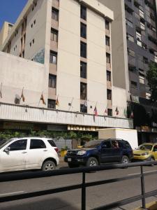 two vehicles parked in front of a building at Hotel Lider in Caracas