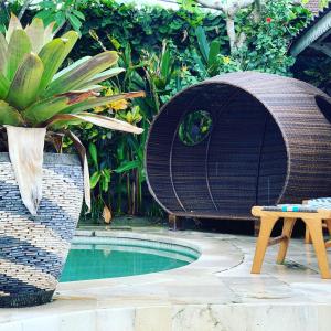 a swimming pool with a wicker chair and a table and a table at Villa Bali Santai in Kerobokan +23 photos