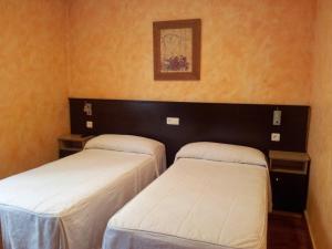 two beds in a room with orange walls at Alojamientos Río Cares in León