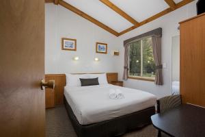 a bedroom with a bed and a table and a window at Lake Hamilton Motor Village and Caravan Park in Hamilton +31 photos