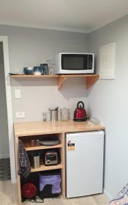 una pequeña cocina con microondas y nevera. en Lawfield en Glenomaru