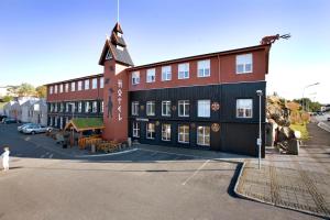 a large building with a clock tower next to a street at Hotel Viking in Hafnarfjördur