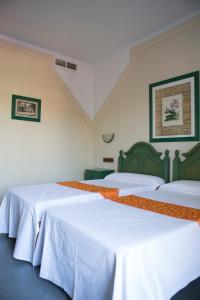 two beds in a room with white sheets at Hotel Mitra Crisálida in Cabra