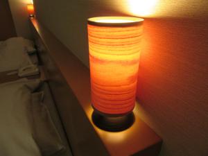 a lamp on a wall next to a bed at Koganezaki Furofushi Onsen in Fukaura