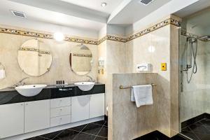 a bathroom with two sinks and two mirrors at Hotel Elms Christchurch, Ascend Hotel Collection in Christchurch