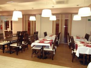 uma sala de jantar com mesas, cadeiras e luzes em Hotel Las Canteras de Puerto Real em Puerto Real