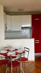 a kitchen with two red tables and chairs and a kitchen with white cabinets at Apartment Lapov in Ičići