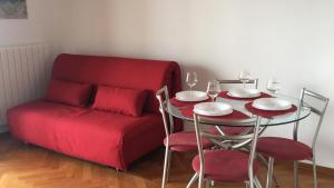 a red couch and a table and chairs with wine glasses at Apartment Lapov in Ičići