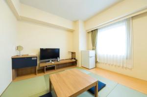 a living room with a television and a table at Dormy Inn Express Mikawaanjo in Anjomachi