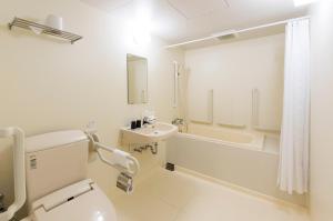 a bathroom with a toilet and a tub and a sink at Dormy Inn Express Mikawaanjo in Anjomachi
