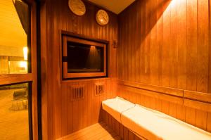a sauna with a tv on a wooden wall at Dormy Inn Express Mikawaanjo in Anjomachi