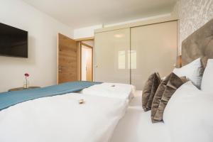 a bedroom with two white beds and a television at Emma's kleines Hotel in Ramsau im Zillertal