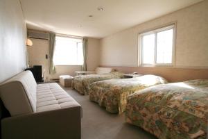 a hotel room with three beds and a couch at Gasthof Melange in Fujikawaguchiko