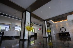 a lobby with two vases with flowers in it at Paco Hotel Guangzhou Baiyun Airport Liantang Metro in Huadu