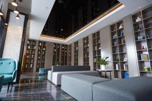 a lobby with couches and chairs and bookshelves at Paco Hotel Guangzhou Baiyun Airport Liantang Metro in Huadu