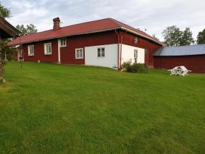 a red and white barn with a grass yard at Backhansgården I Plintsberg in Tällberg