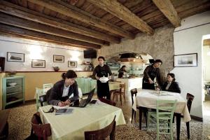 a group of people sitting at tables in a kitchen at Casa - hiša Klarčeva in Ceróglie dellʼErmada