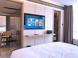 a bedroom with a bed and a flat screen tv at Paco Hotel Guangzhou Baiyun Airport Liantang Metro in Huadu