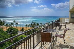 un balcón con sillas y mesas y la playa en @ Marbella Lane Mountain View Studio, steps from Wakiki Beach en Honolulu