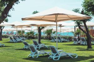 a group of chairs and an umbrella on the grass at Paloma Orenda in Side