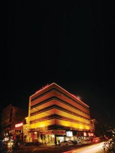 um grande edifício com luzes amarelas numa rua à noite em Smart Hotel em Lahore