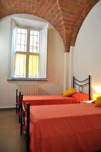 um quarto com 2 camas com lençóis vermelhos e uma janela em La casa di Dario, Dario's house. em Pisa