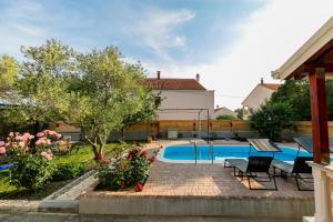 uma piscina num quintal com cadeiras e flores em Vacation home Duilo em Donji Zemunik