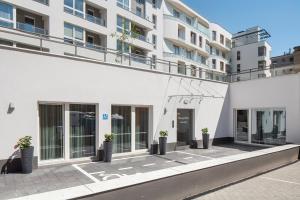 a white building with potted plants in front of it at Sleepy3city Apartments Batorego 9 in Gdynia