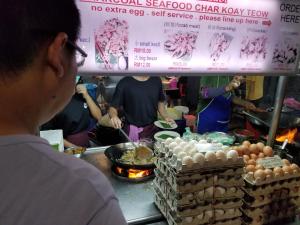 a man standing in front of a food stand at Yan Hotel in George Town