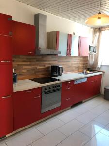 a kitchen with red cabinets and a stove top oven at Apartment BLN in Oststeinbek