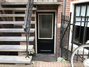 una porta nera su una casa di mattoni con scale di 16 sous a Utrecht