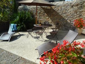 eine Terrasse mit einem Tisch, Stühlen und einem Sonnenschirm in der Unterkunft Gîtes du Vieux Tilleul, l'Ecurie. in Marseillette