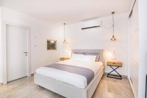 a white bedroom with a bed and a night stand at The suite in Eilat