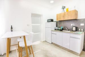 a white kitchen with a table and a white refrigerator at The suite in Eilat