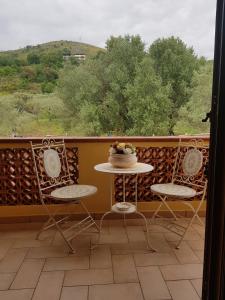 einen Balkon mit 2 Stühlen und einem Tisch mit Kuchen darauf in der Unterkunft Villa Degli Ulivi in Santa Maria del Cedro