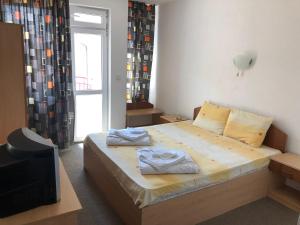 a bedroom with a bed and a tv and a window at Хотел Милев in Kiten