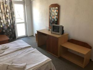 a room with a bed and a tv on a desk at Хотел Милев in Kiten