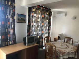 a living room with a tv and a table and a curtain at Хотел Милев in Kiten