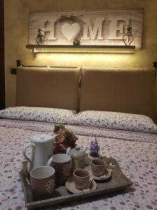 ein Tablett mit Tassen und Untertassen auf dem Bett in der Unterkunft Villa Degli Ulivi in Santa Maria del Cedro