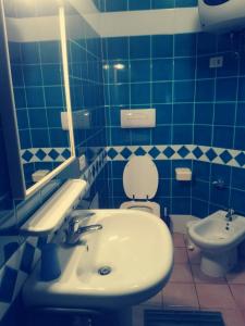 W wyłożonej niebieskimi kafelkami łazience znajduje się umywalka i toaleta. w obiekcie Appartamento In Residence w mieście Santa Teresa Gallura +8 zdjęć