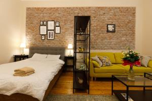a bedroom with a bed and a yellow couch at Stylish Flat in the Heart of Historical Center in Timişoara