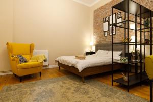 a bedroom with a bed and a yellow chair at Stylish Flat in the Heart of Historical Center in Timişoara
