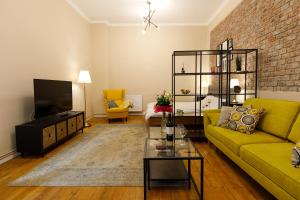 a living room with a yellow couch and a tv at Stylish Flat in the Heart of Historical Center in Timişoara