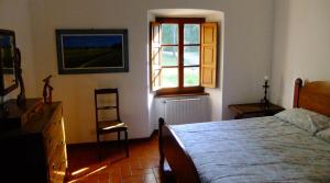 a bedroom with a bed and a window and a chair at Convento del Carmine 4 in Fivizzano