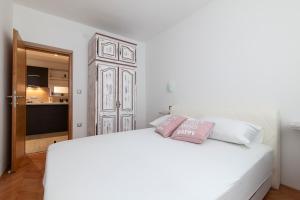 a bedroom with a white bed with two pillows on it at Apartment Svemir in Primošten